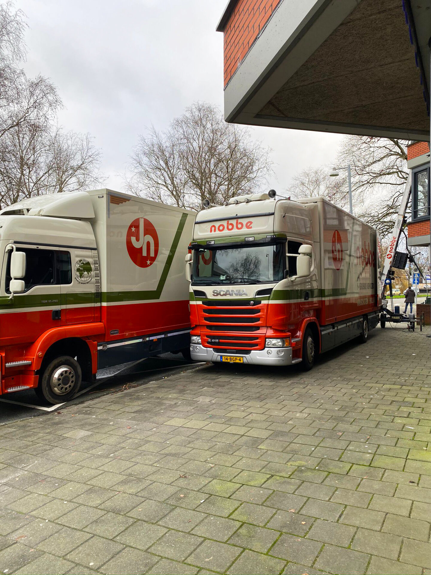 Twee verhuiswagens van Verhuisbedrijf Nobbe met op de achtergrond de verhuislift.